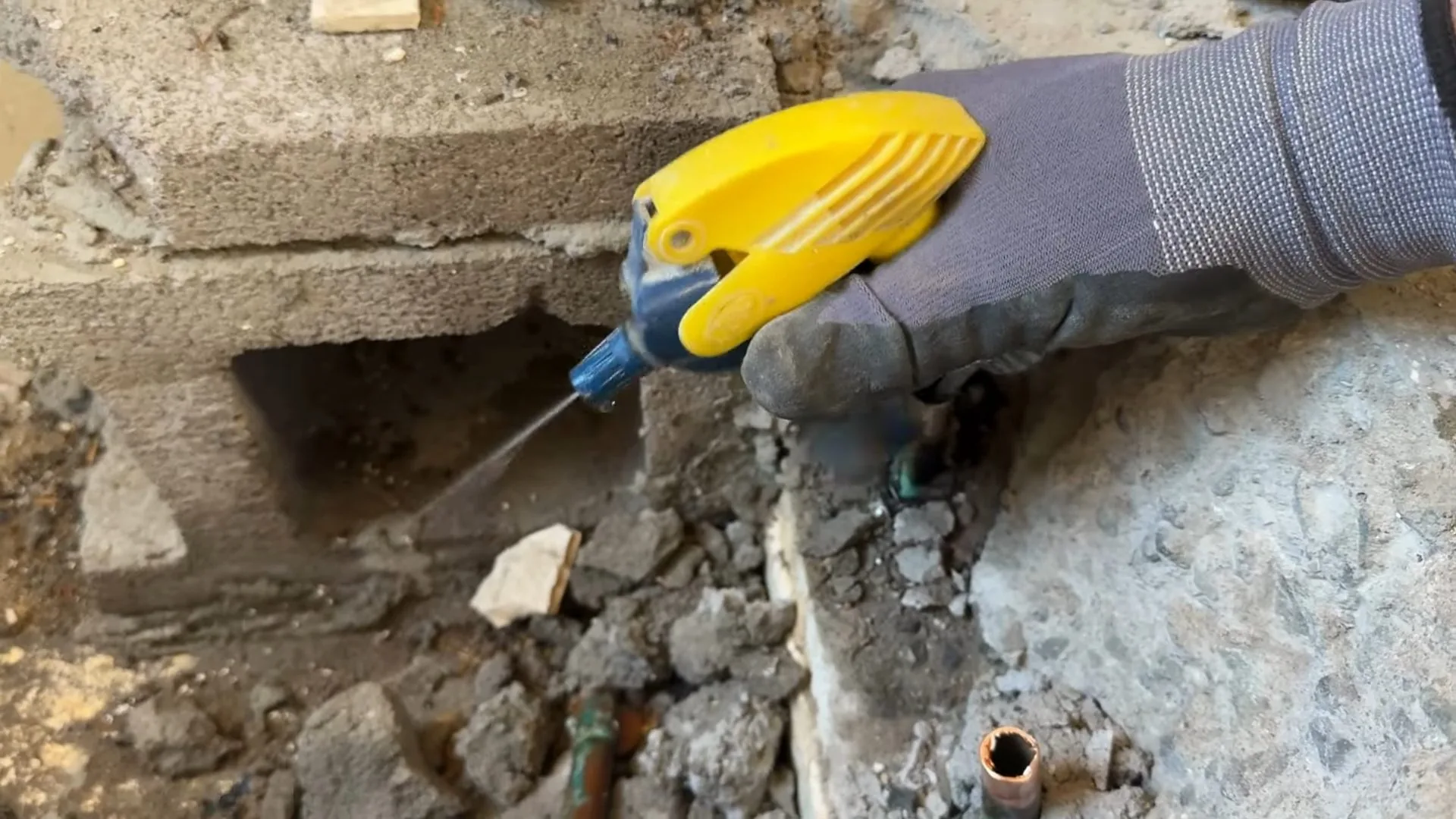 A plumber working with the plumber breaking bathroom tile floor as part of a emergency plumber call.
