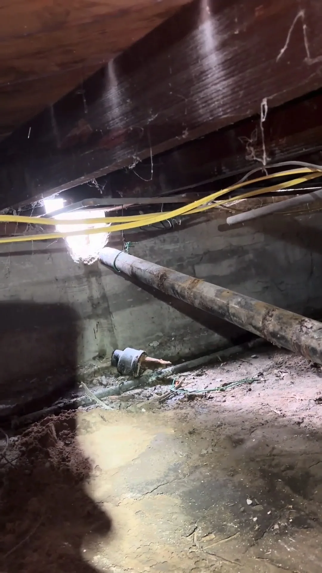 Detail of the plumber crawling through low clearance space seen during emergency plumber service.